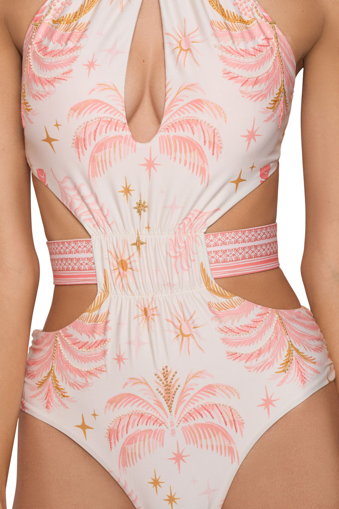 A model casually posing, wearing the Barbie High Neck One Piece Swimsuit, a one piece set, with handmade embroidery details, a halter neck, with opening details, sexy cutouts and a scrunch belt, with ties at the back and a moderate bottom coverage.